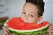 Caucasian boy with expressive eyes, taking a bite of a juicy watermelon.jpeg