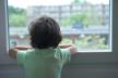 dječak gleda kroz prozor i čeka da prođe kriza s koronavirusom