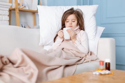 Steps to recovery. Pleasant ill little girl lying on the couch and drinking tea while suffering from cold.jpg