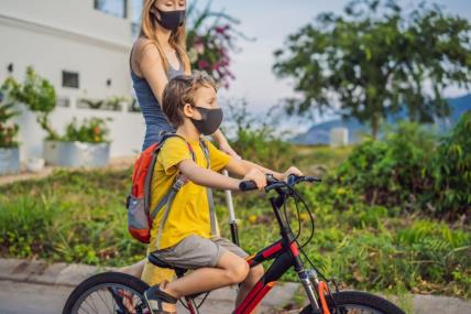 dijete vozi bicikli s maskom na licu zbog koronavirusa