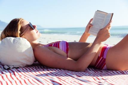 žen ačita knjigu na plaži