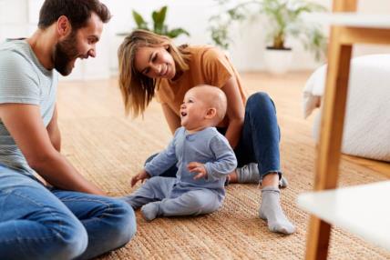 Parents-Sitting-On-Floor-At-Home-Playing-With-Baby-Son.jpg