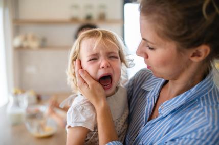 Mama u naručju drži dijete koje ima tantrum